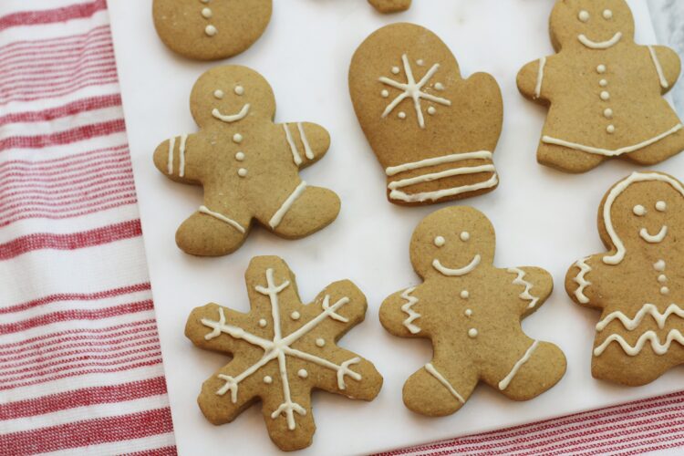 Gingerbread cookies with white icing on a white cutting board with a red and white striped background