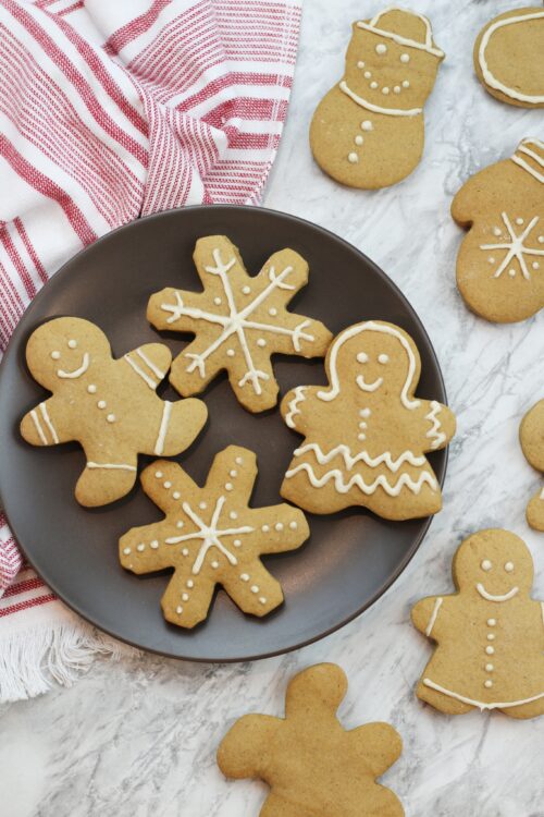 Gingerbread cookies with white icing on plate with a red and white striped napkin