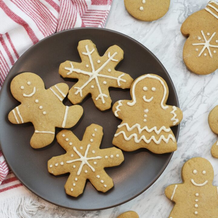 Gingerbread cookies with white icing on plate with a red and white striped napkin