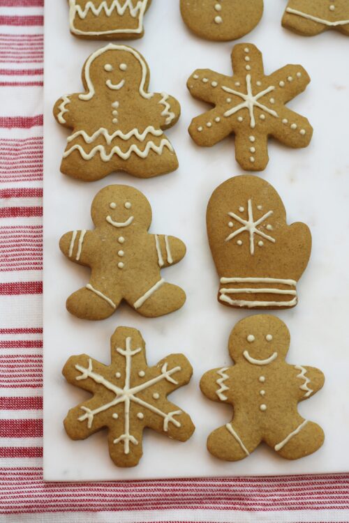 Gingerbread cookies with white icing on a white cutting board with a red and white striped background